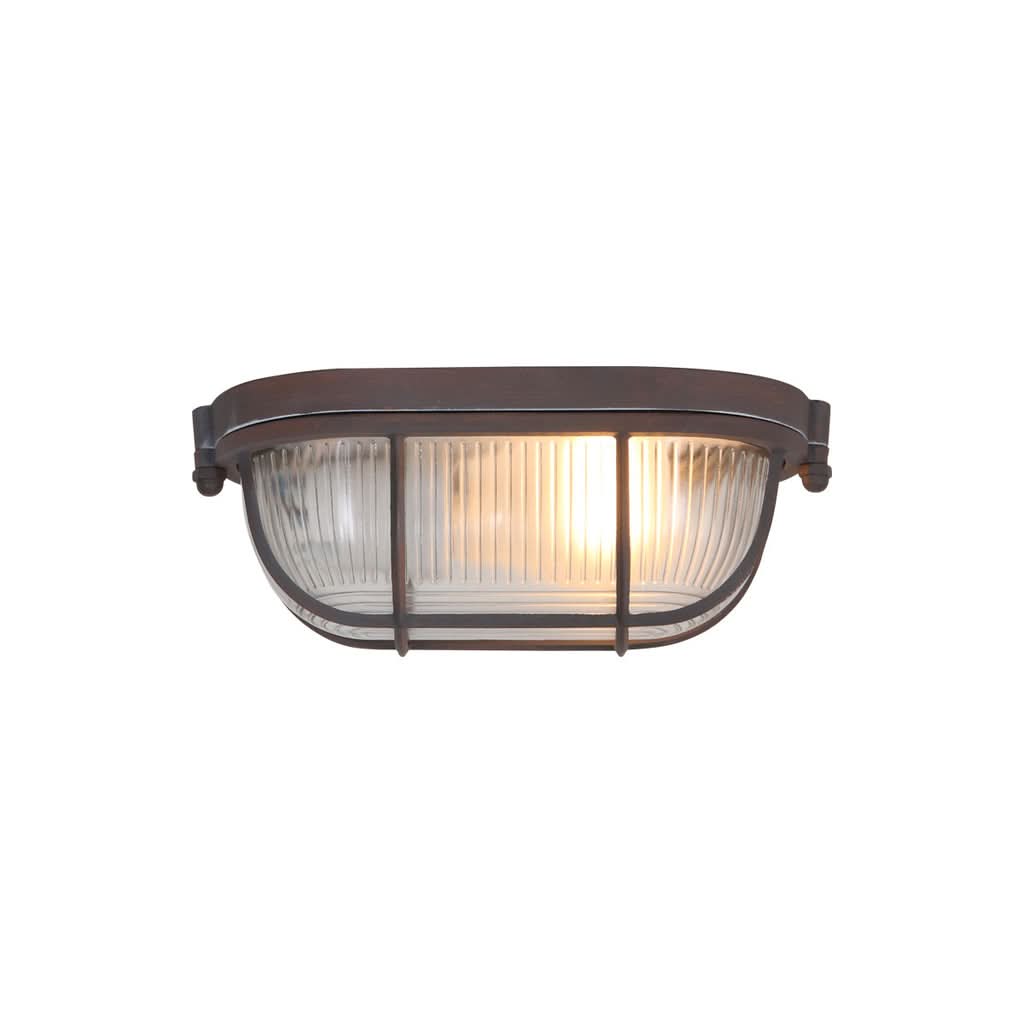 Vue de face du plafonnier allumé, verre strié et grille métallique sombre.