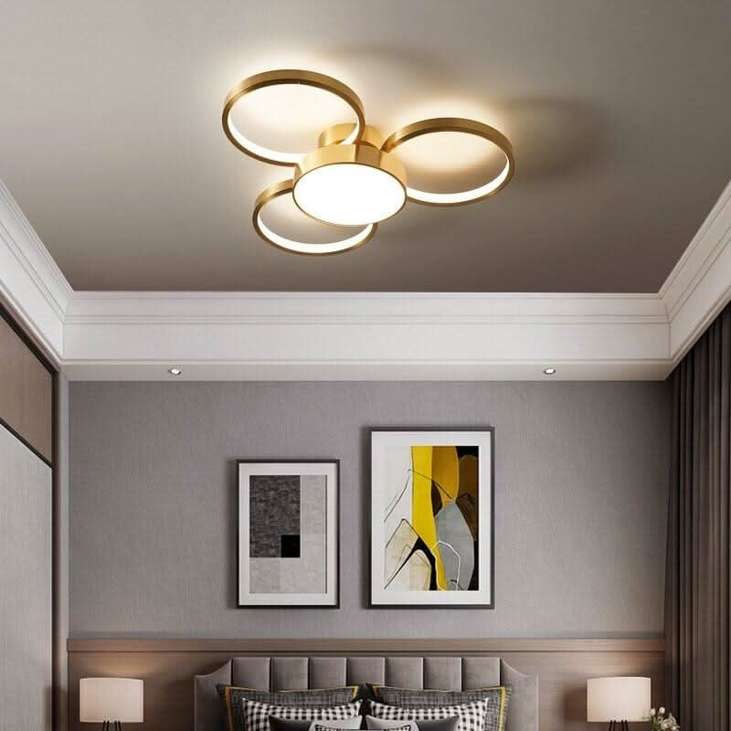 Plafonnier doré à trois anneaux lumineux installé au plafond d'une chambre grise