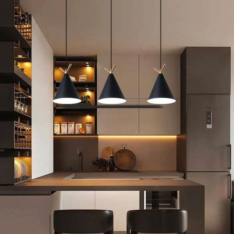 Suspensions noires à détail doré éclairant un plan de travail de cuisine en ambiance chaleureuse