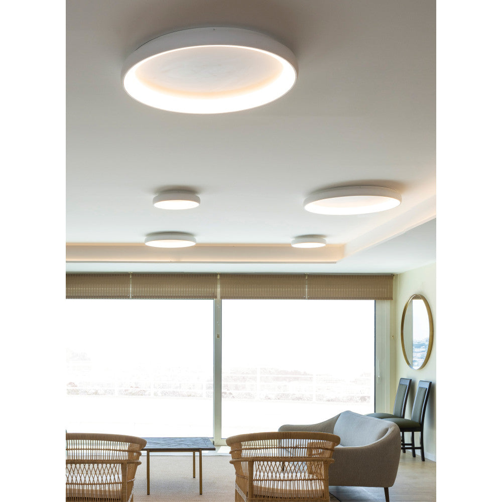Mise en ambiance dans un séjour, plusieurs plafonniers ronds blancs fixés au plafond.