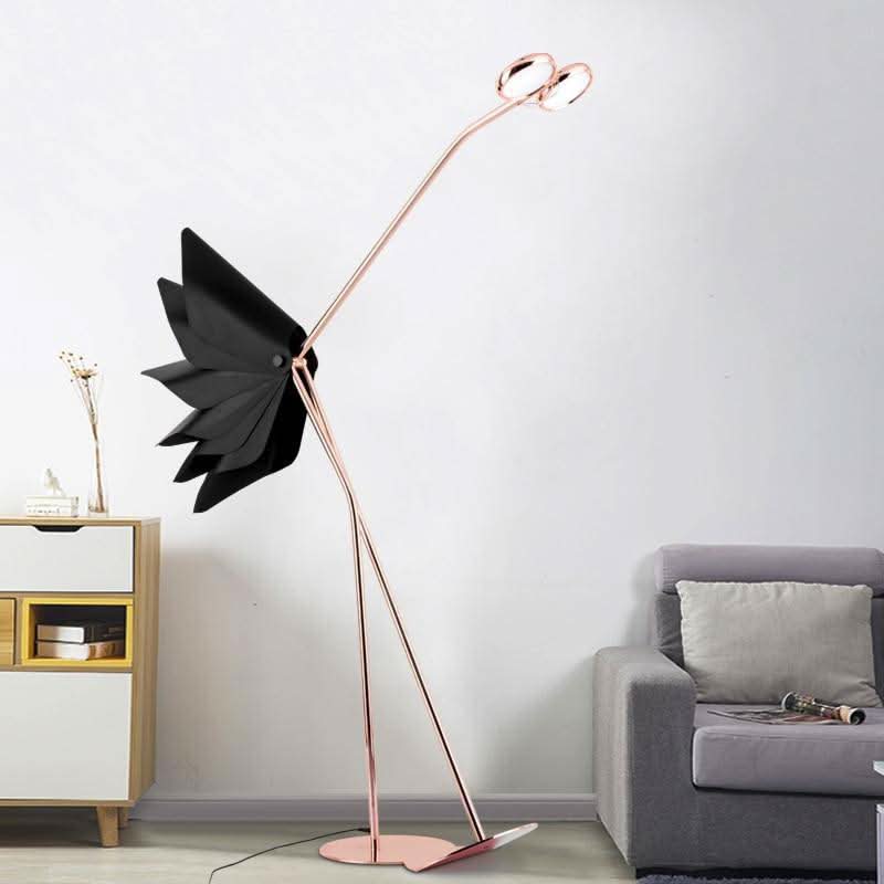 Lampadaire rose doré installé dans un salon près d'un canapé gris