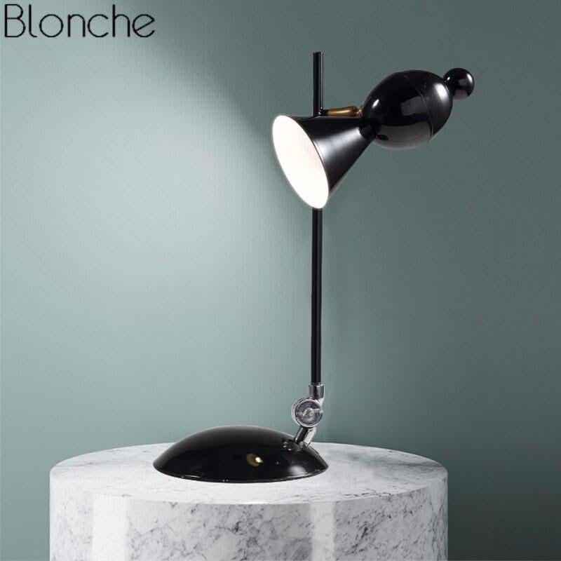 Lampe noire posée sur table en marbre, fond vert, abat-jour orientable éclairé, vue latérale.