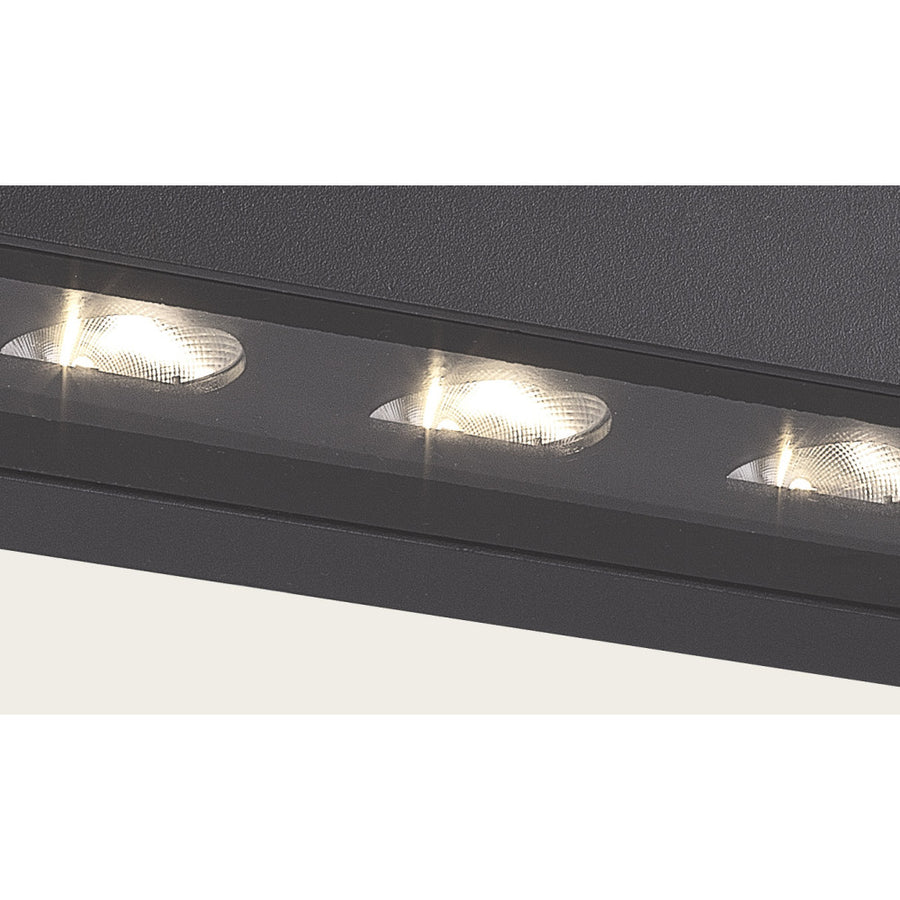 Gros plan sur les trois optiques LED striées et la finition graphite texturée du boîtier