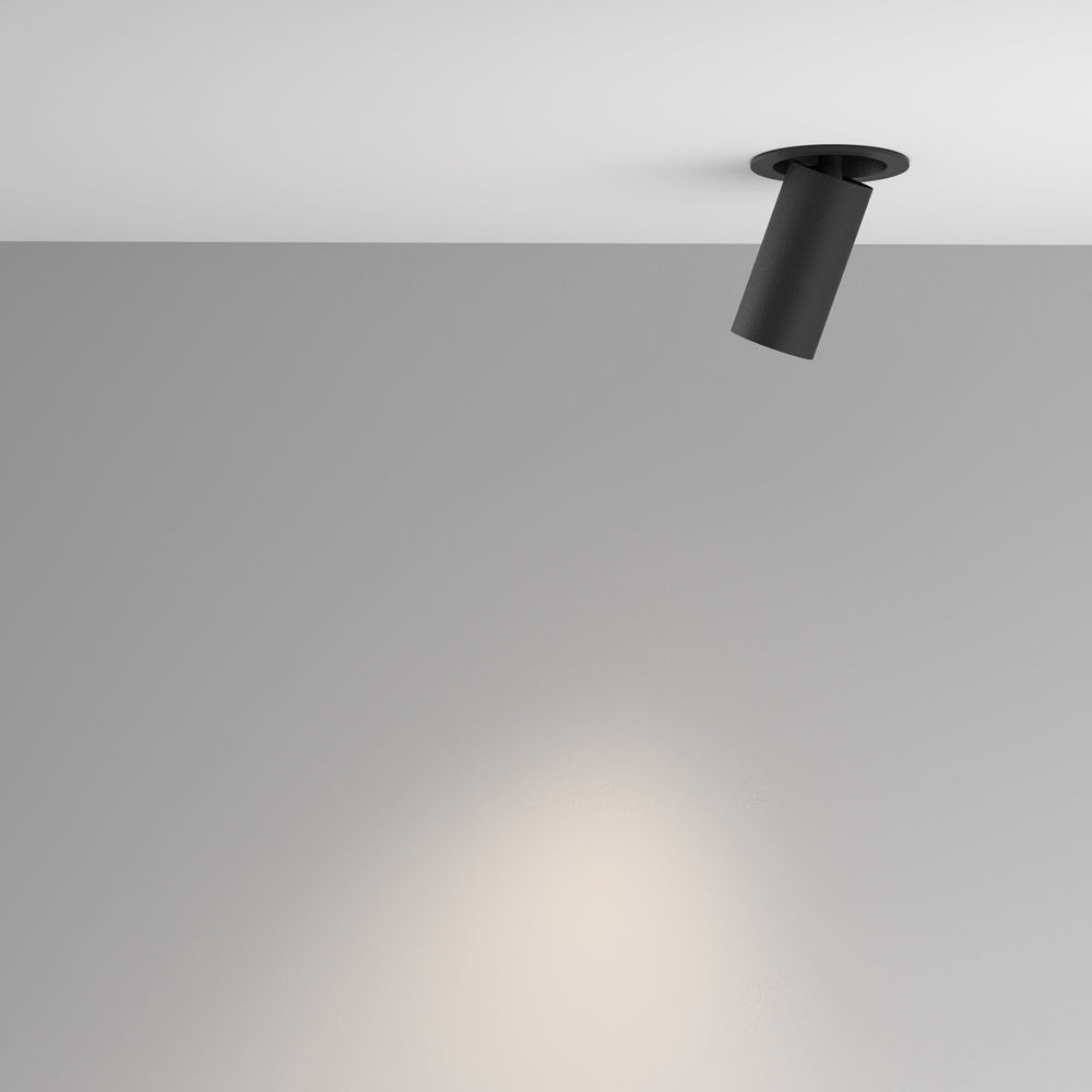 Spot incliné au plafond éclairant un mur gris dans une pièce vide