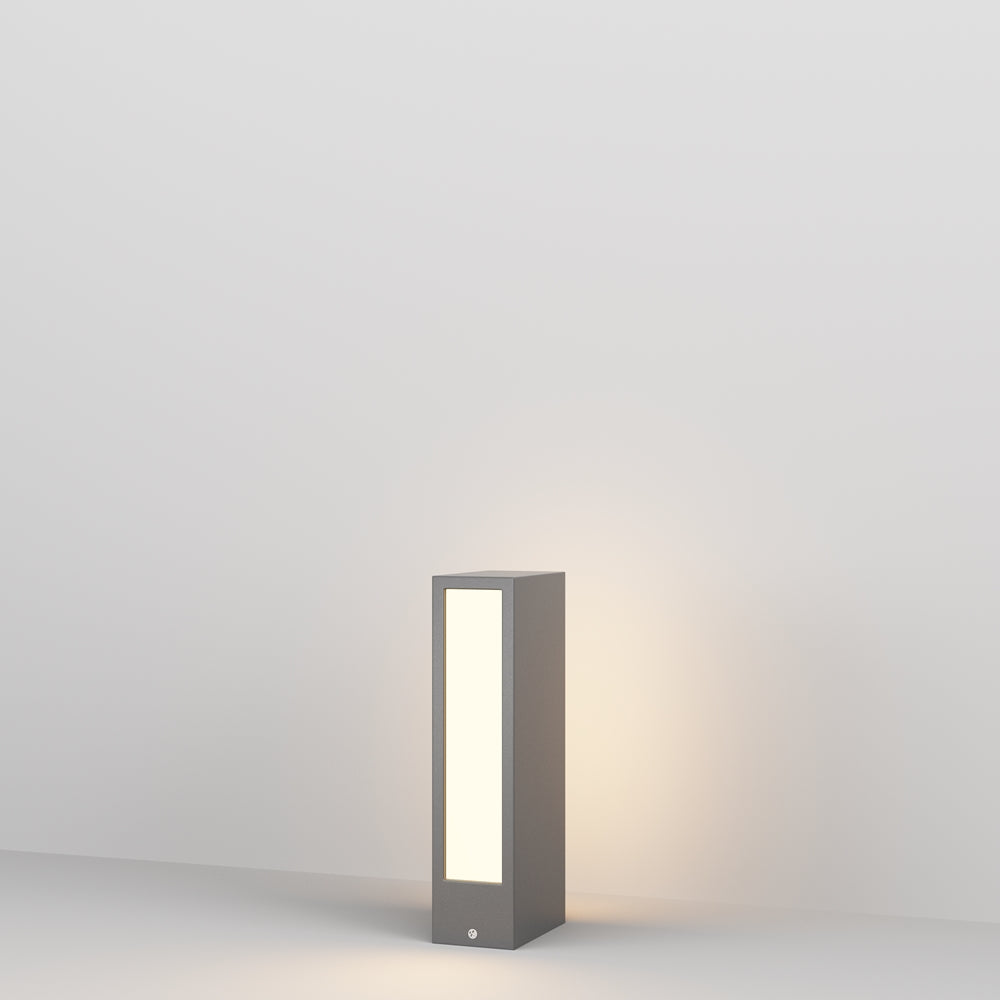 Vue de face du luminaire extérieur gris, posé au sol, panneau lumineux allumé.