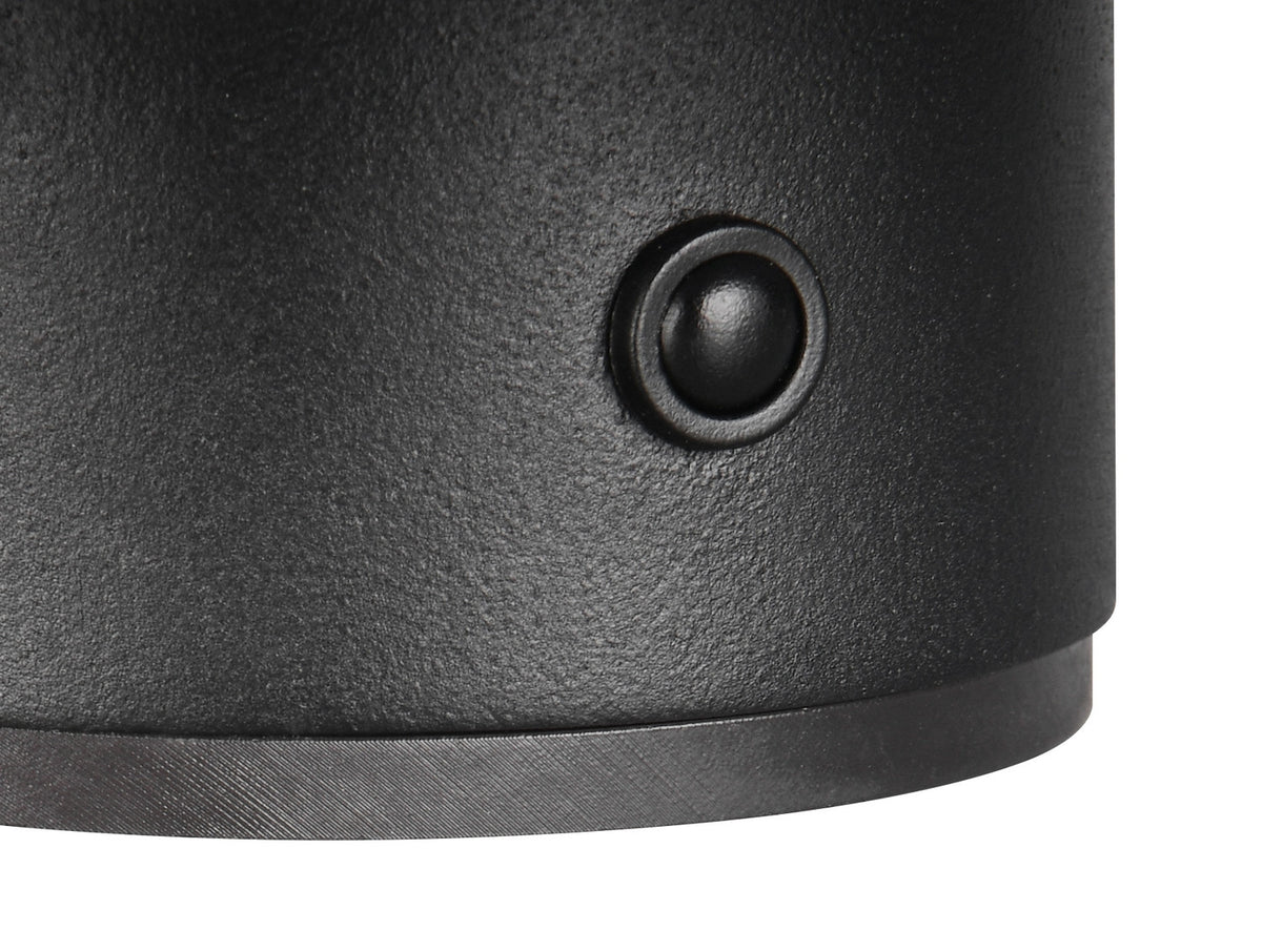 Détail macro de la finition texturée noire mate et d'un petit bouton circulaire en relief