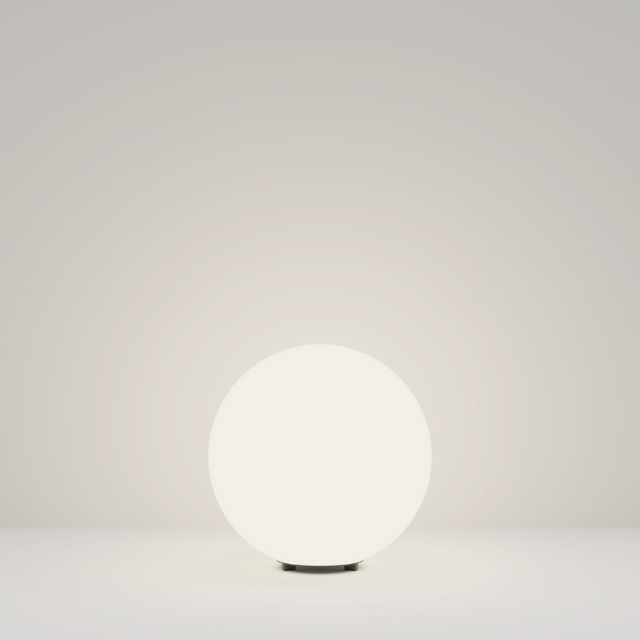 Vue d'ensemble du luminaire sphérique blanc éclairé, posé sur fond neutre