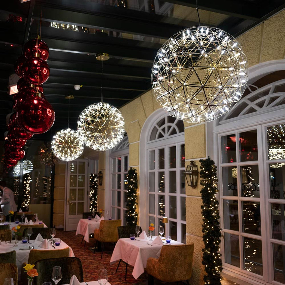 Ambiance restaurant de fête avec suspensions boules lumineuses et décorations rouges suspendues.