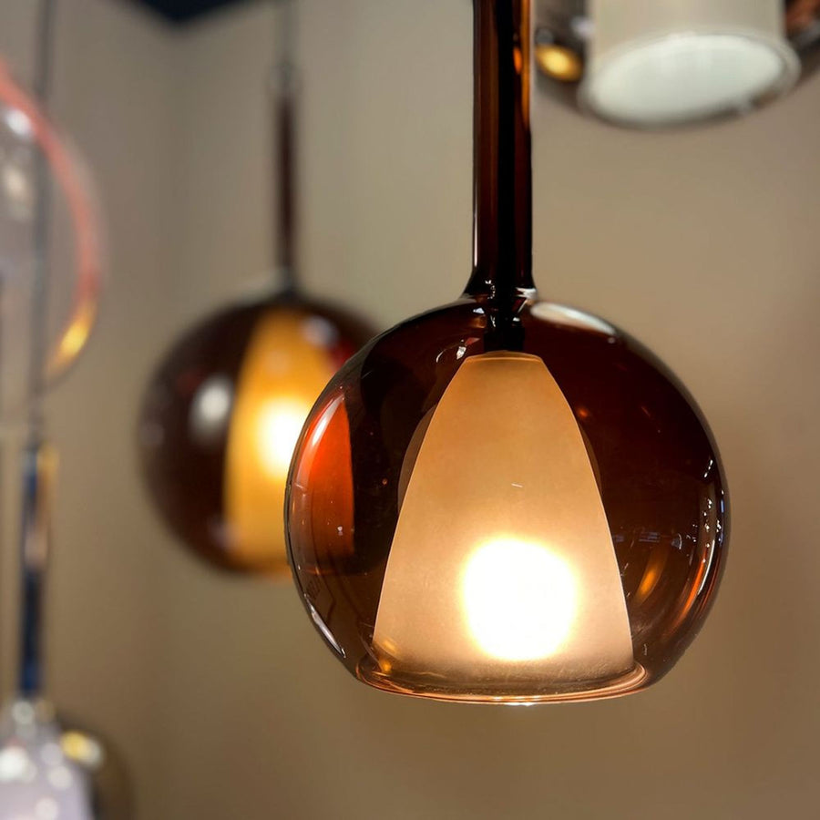 Gros plan sur une sphère de verre ambré et son abat-jour interne allumé