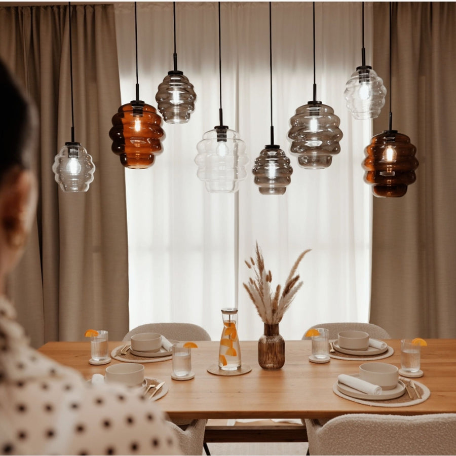 Table dressée avec vaisselle et vase, les huit suspensions forment une ligne devant les rideaux