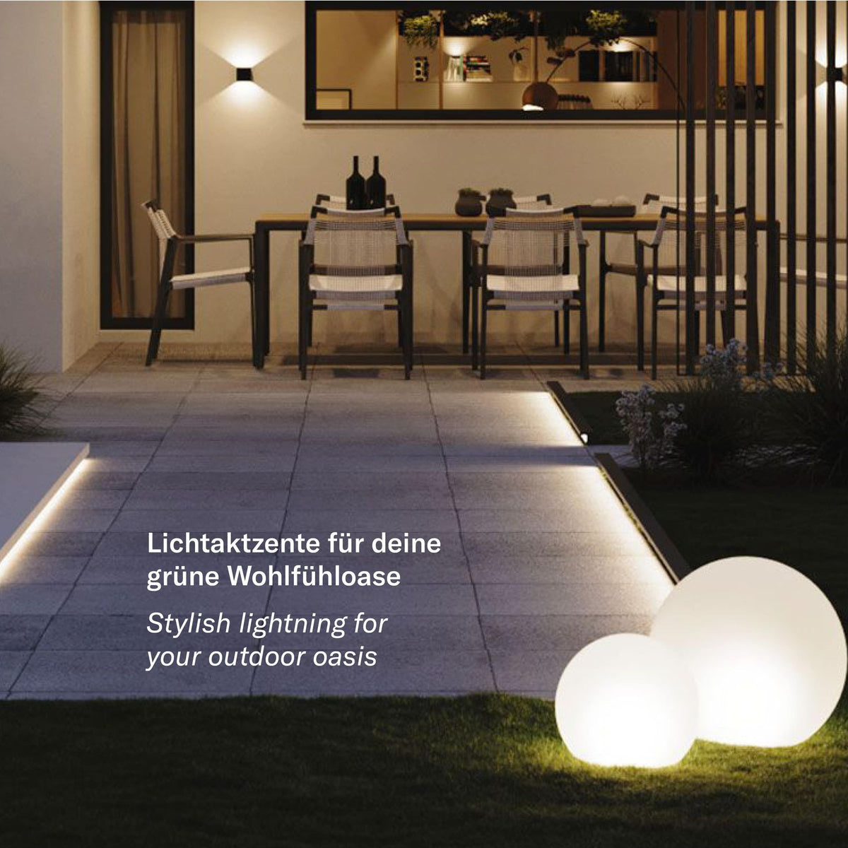 Deux globes lumineux dans l'herbe au bord d'une terrasse avec mobilier