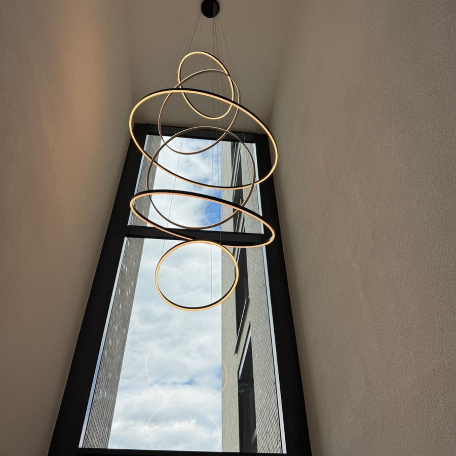Grande suspension aux nombreux cercles dorés superposés dans une cage d'escalier