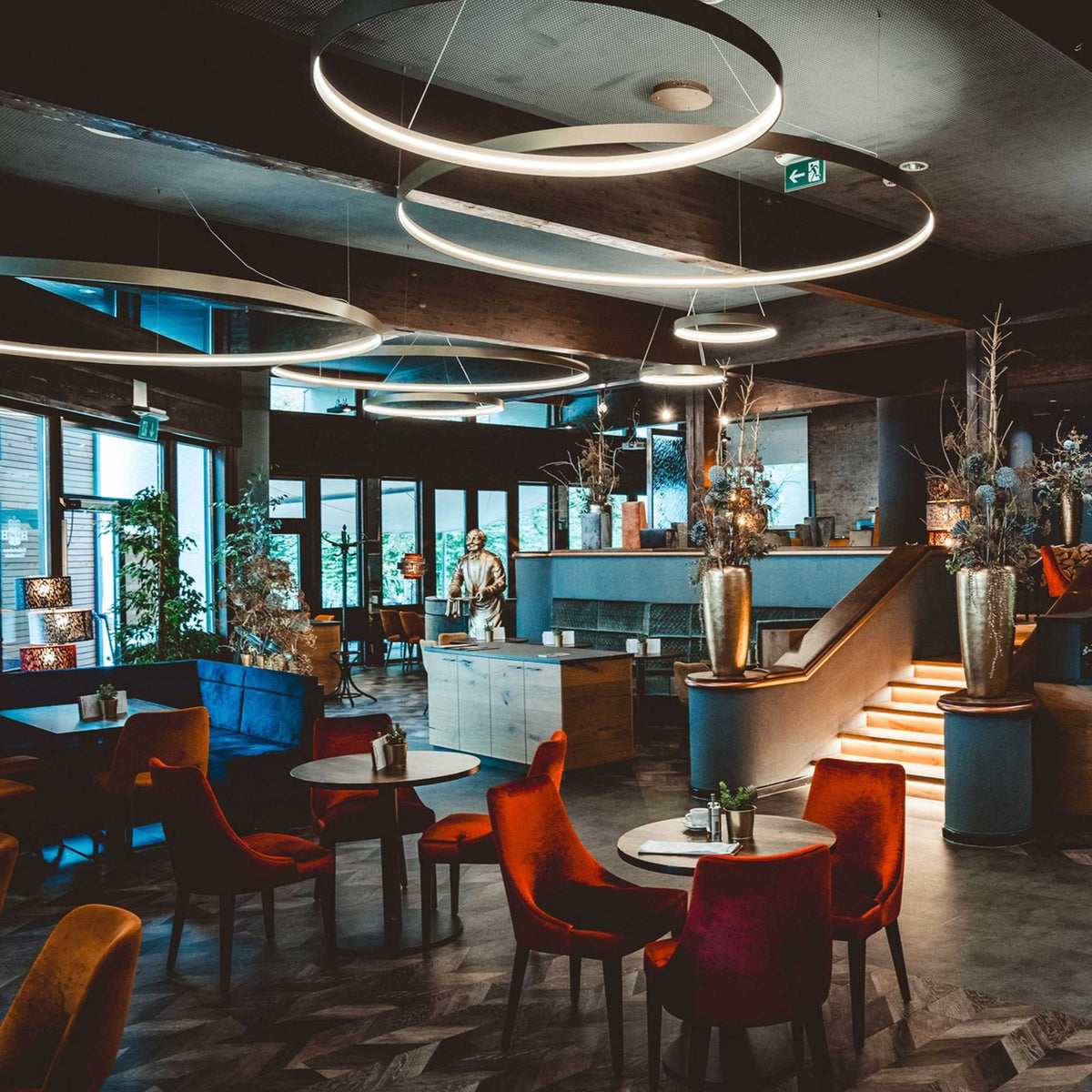 Anneaux lumineux suspendus au-dessus des tables d'un restaurant au décor sombre