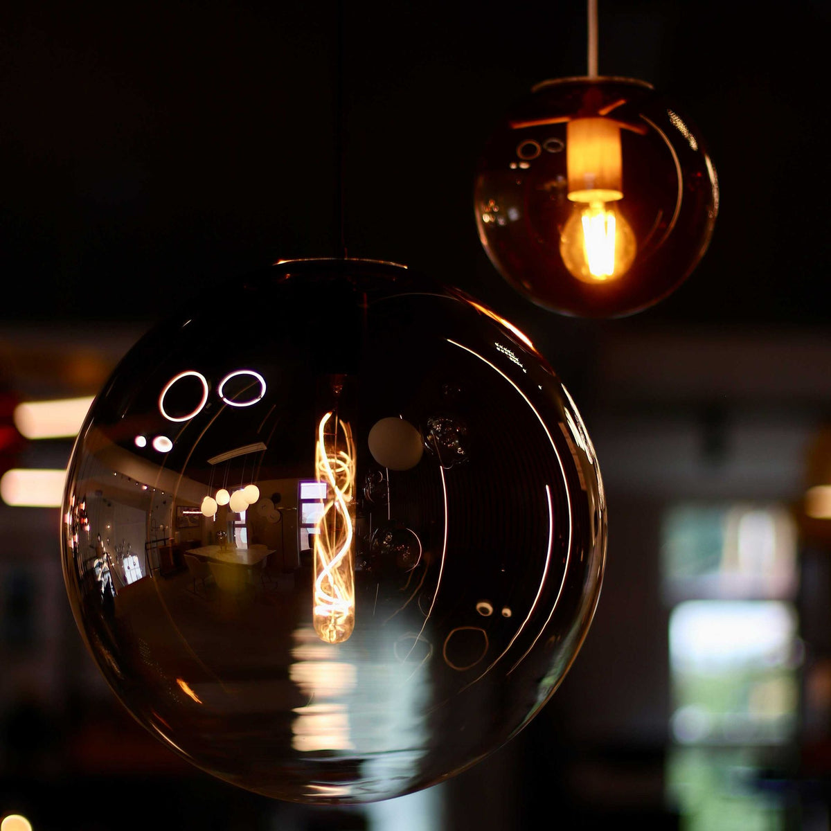 Détail nocturne de deux globes en verre ambré, ampoule allumée à l'intérieur