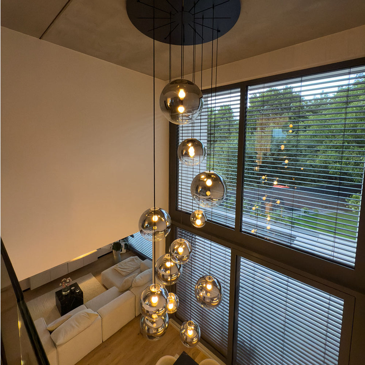 Vue d'ensemble du salon double hauteur avec canapé blanc et grandes baies vitrées.