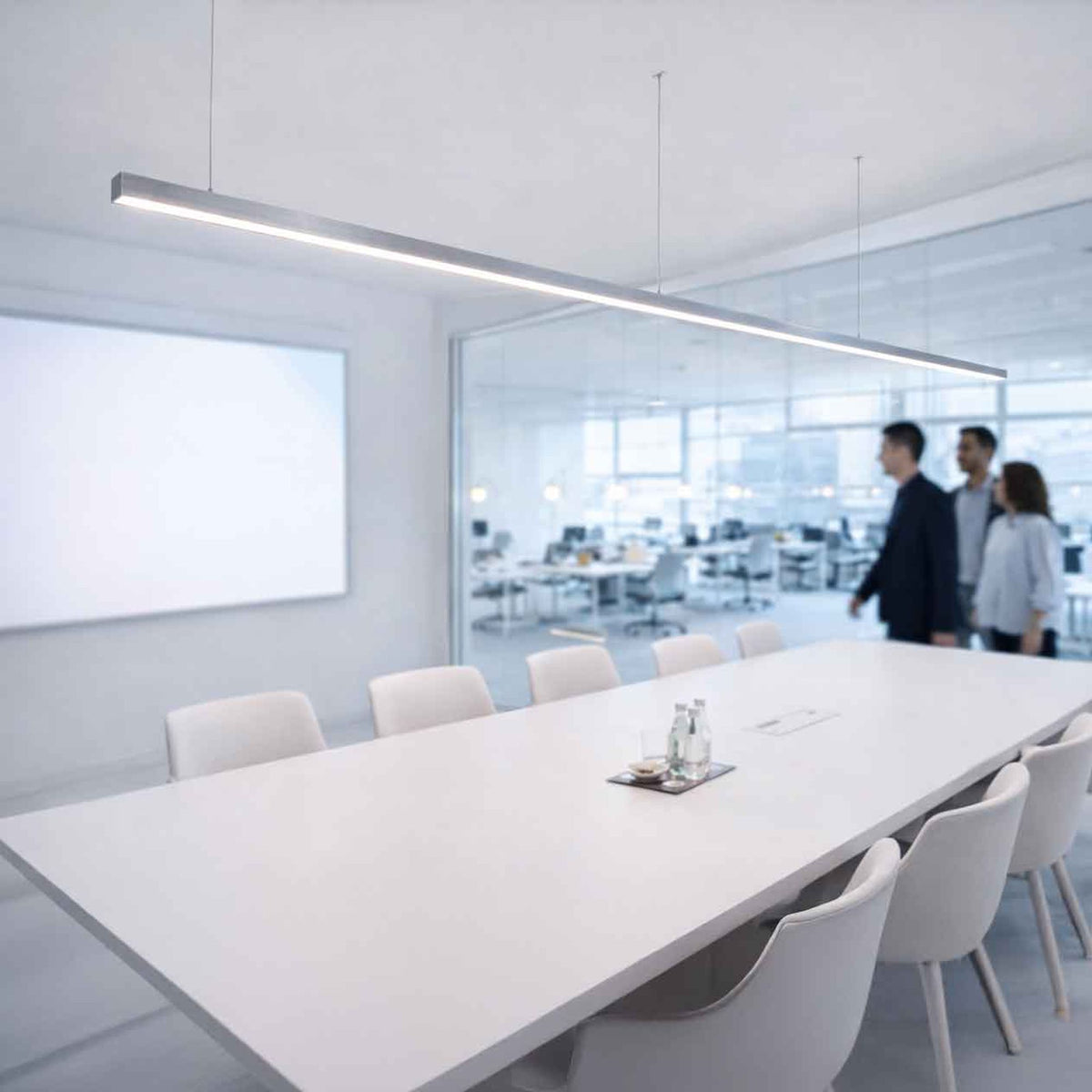 Suspension linéaire blanche allumée au-dessus d'une longue table de réunion en bureau vitré