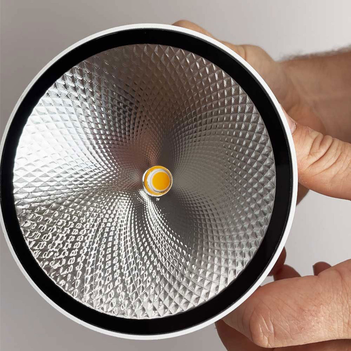 Détail du réflecteur aluminium facetté et de la led COB centrale tenu en main