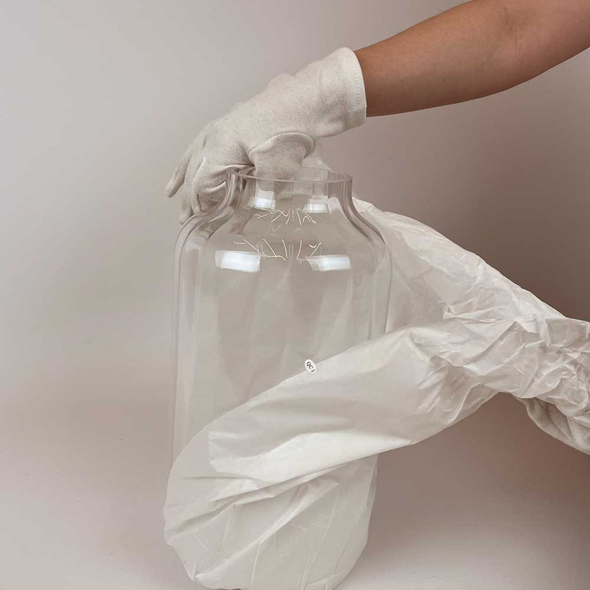 Verre cylindrique transparent déballé avec des gants blancs par une main