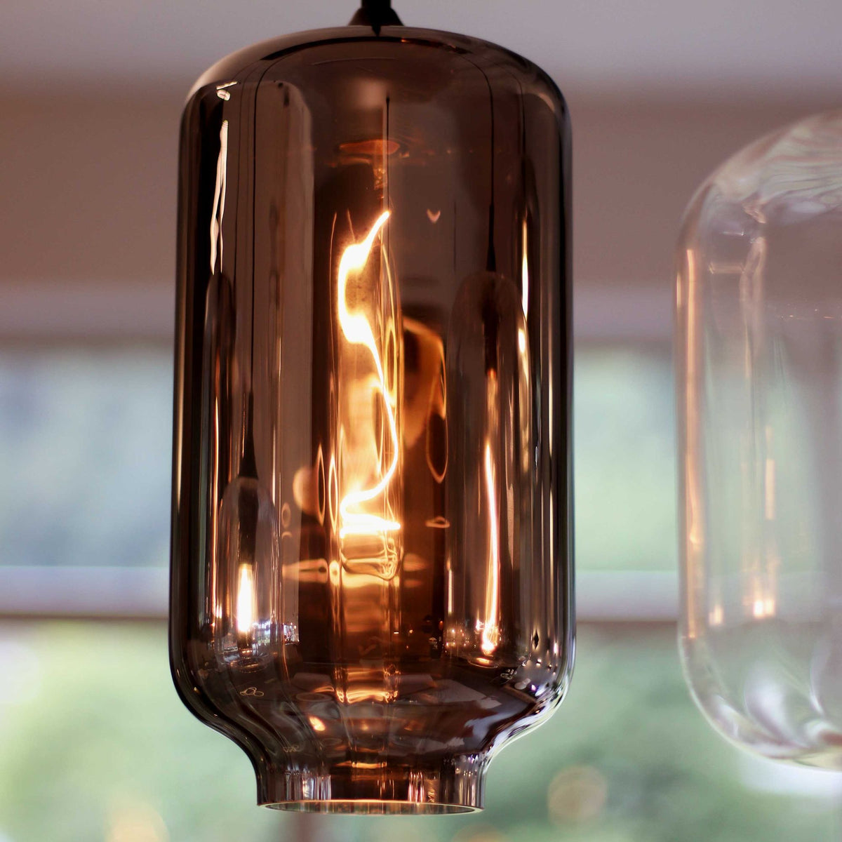 Détail rapproché du grand verre fumé et de l'ampoule filament allumée