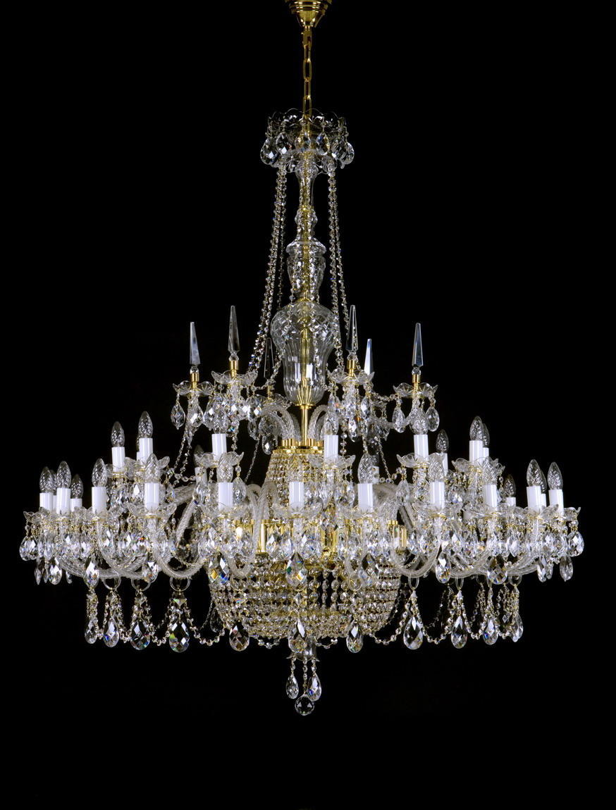 Lustre en cristal doré à bras multiples photographié de face sur fond noir