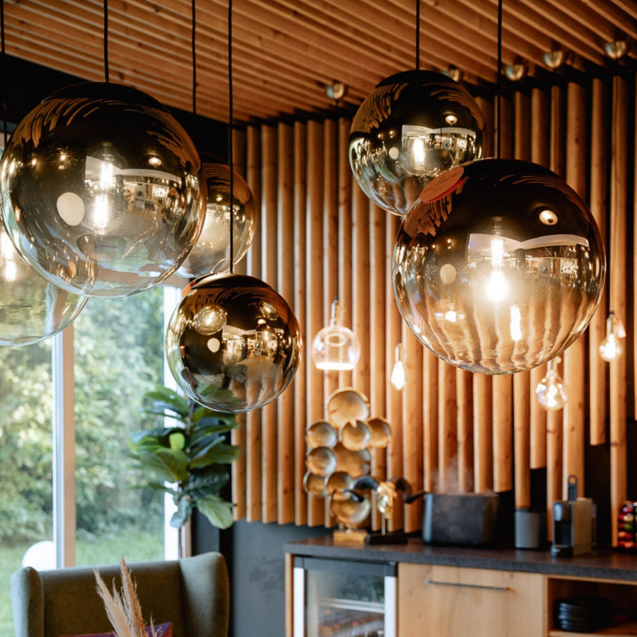 Grands globes suspendus aux reflets dorés devant un mur de lattes en bois, au-dessus d'un comptoir.