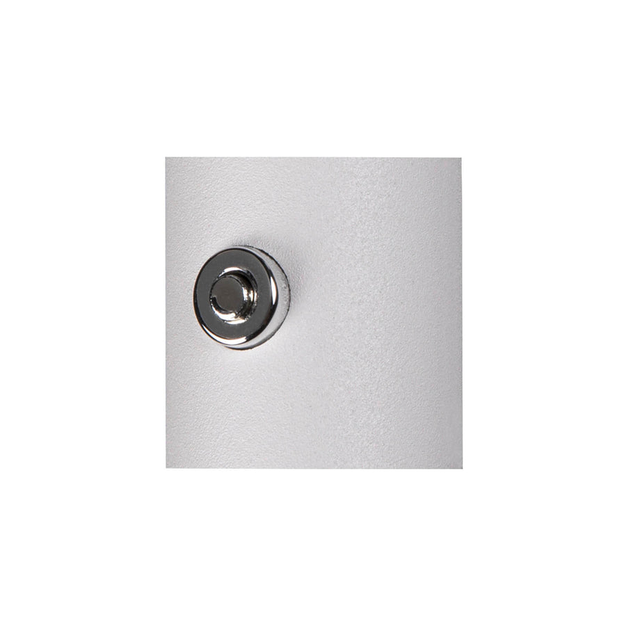 Gros plan sur le bouton-poussoir chromé intégré à la surface blanche mate de l'applique.