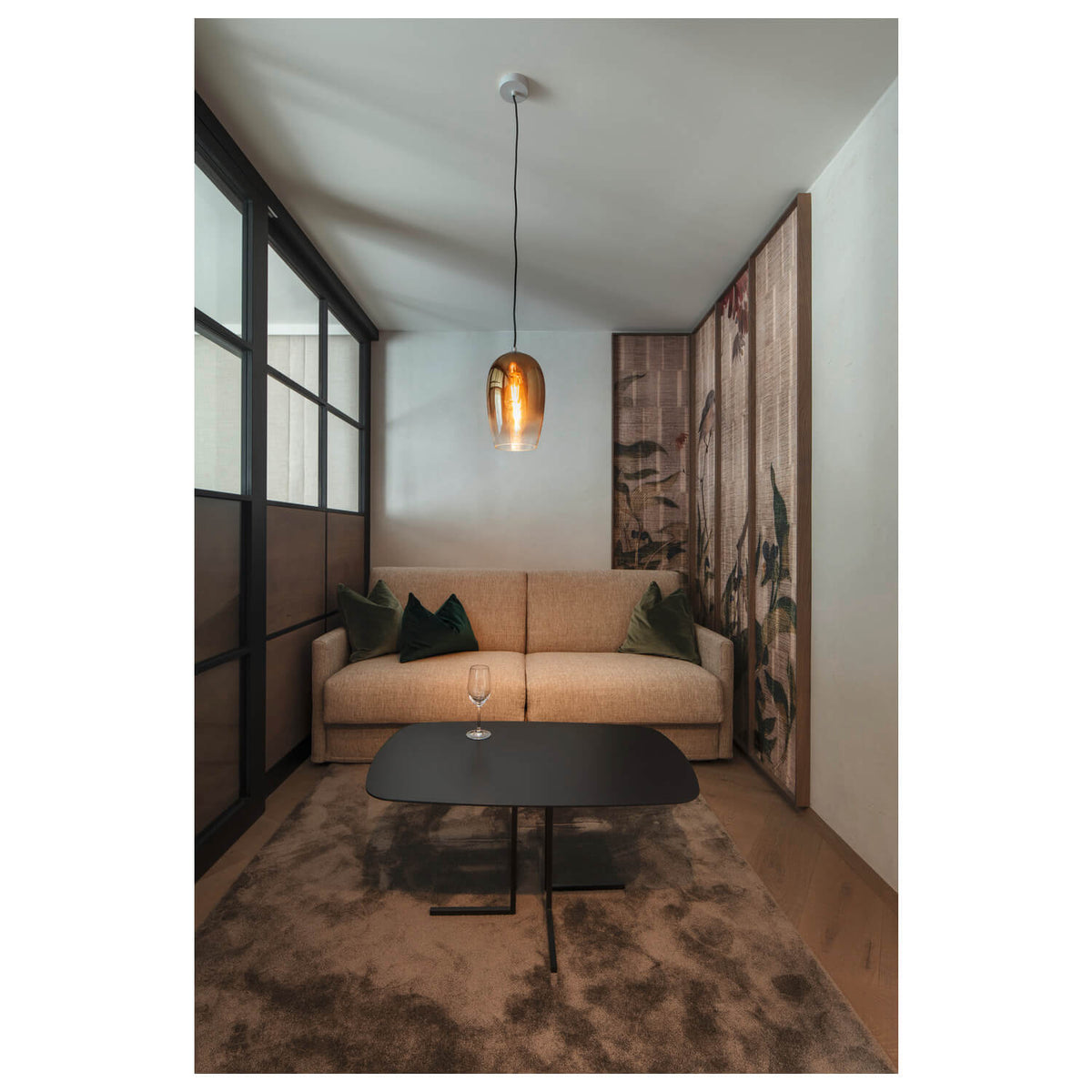 Mise en ambiance dans un salon, suspension allumée au-dessus d'une table basse.