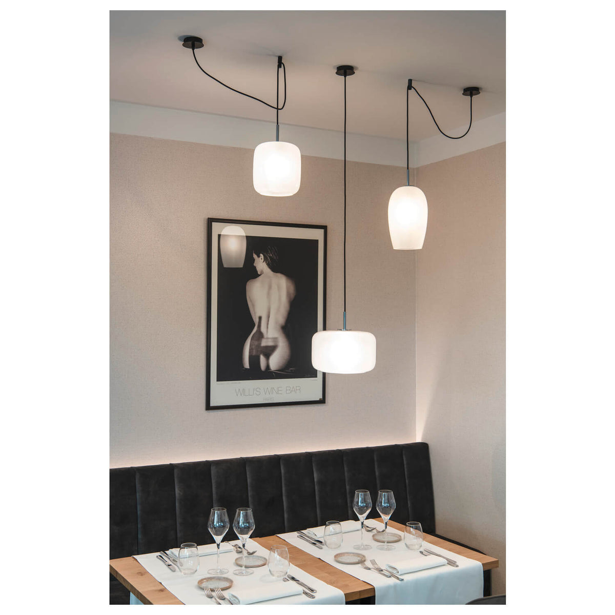 Mise en ambiance au-dessus d'une table de restaurant, plusieurs suspensions blanches éclairant la scène.