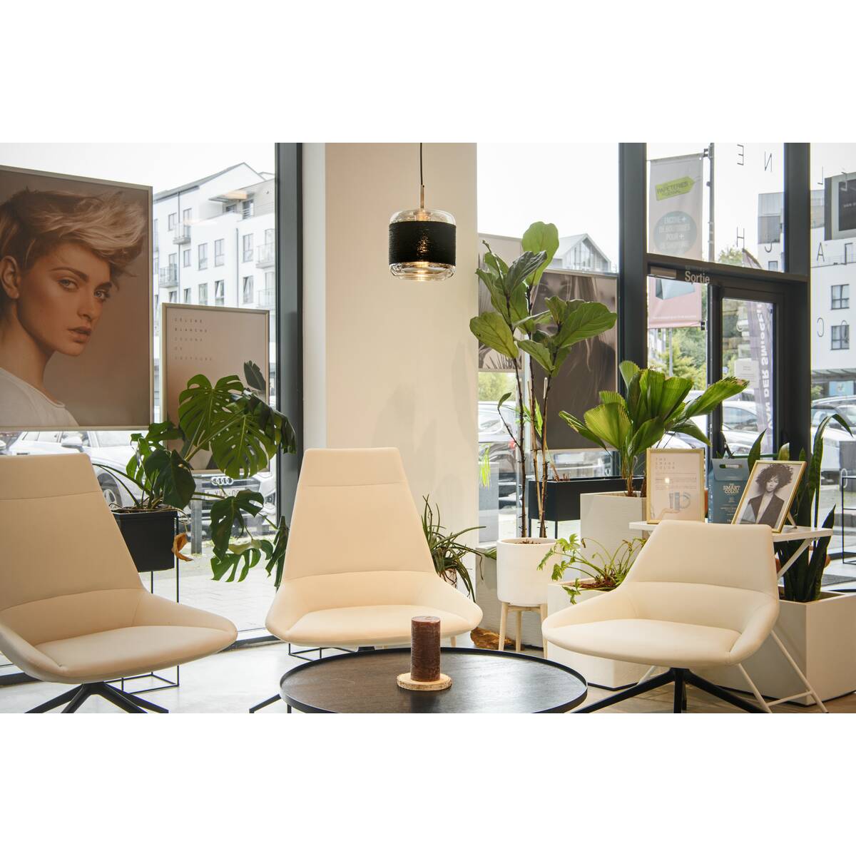 Suspension installée dans un espace salon avec chaises blanches et plantes vertes.