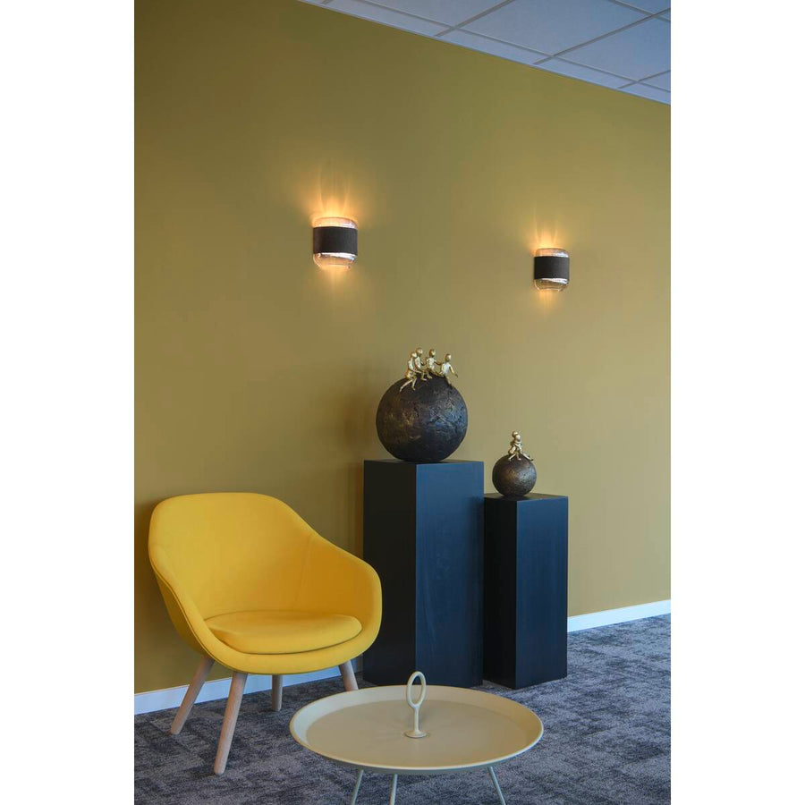 Salon contemporain avec fauteuil jaune et deux appliques murales sur un mur olive
