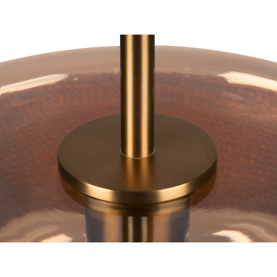 Détail du support métallique doré et de la tige fixée sur le verre ambré.