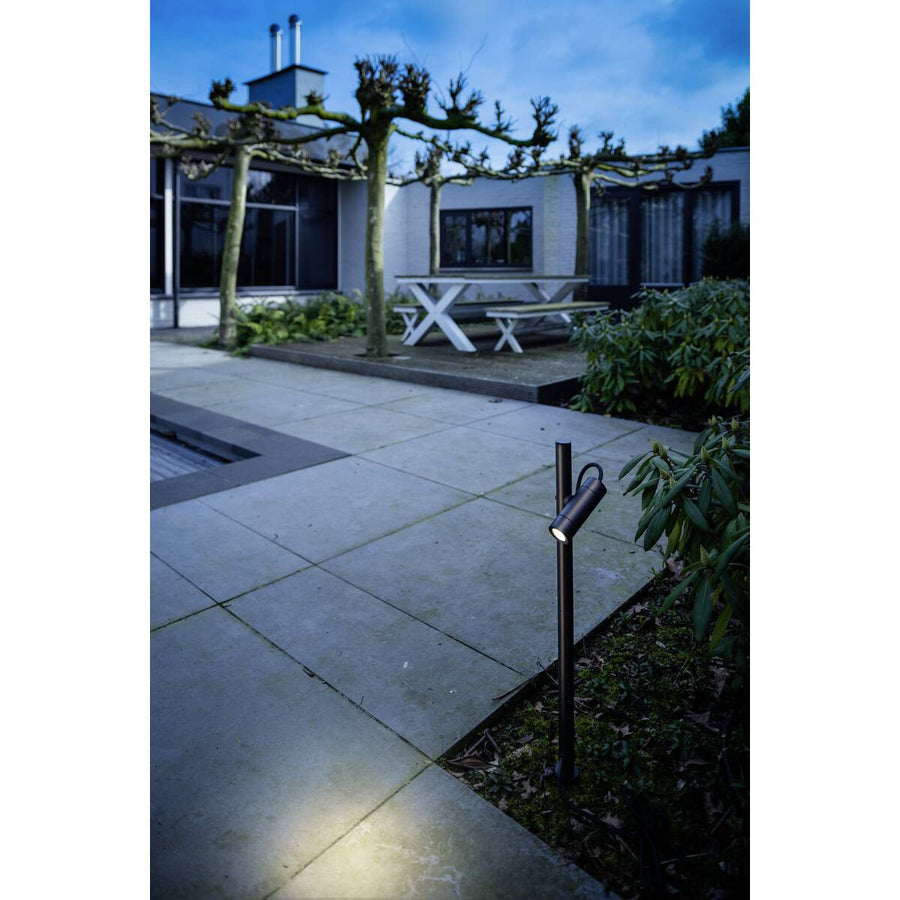 Mise en situation sur une terrasse au crépuscule, luminaire planté au bord des dalles.
