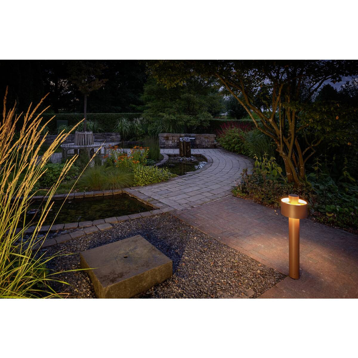 Mise en ambiance du lampadaire éclairant une allée de jardin au crépuscule