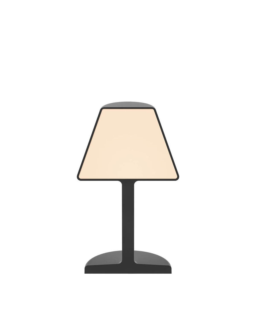 Vue de face de la lampe noire, abat-jour trapézoïdal et embase plate arrondie.