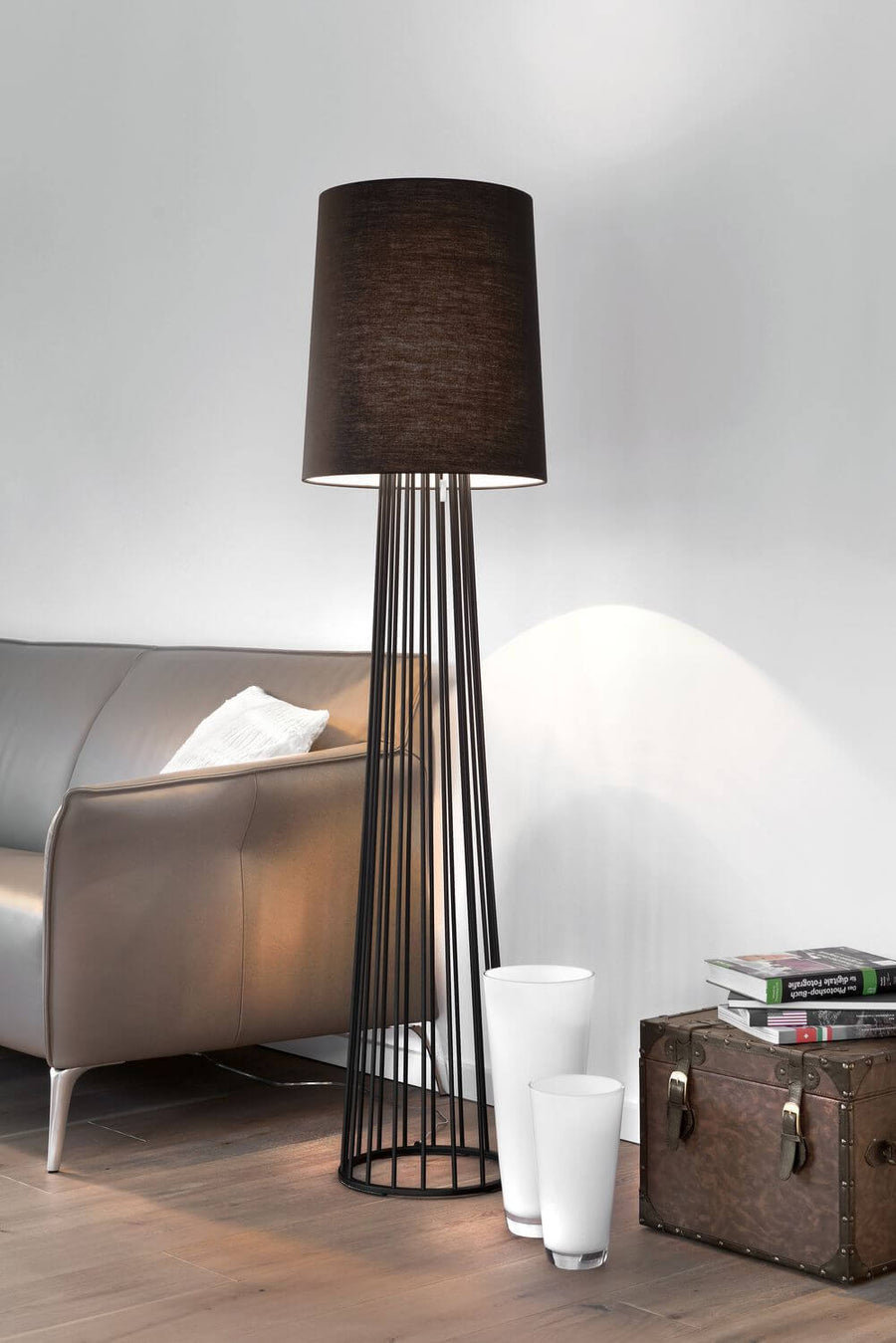 Lampadaire en situation devant un canapé taupe, avec coffre ancien et vases blancs