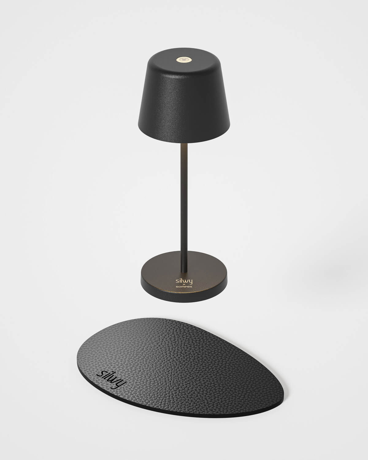 Lampe noire sur fond blanc, socle ovale gravé posé devant en bas