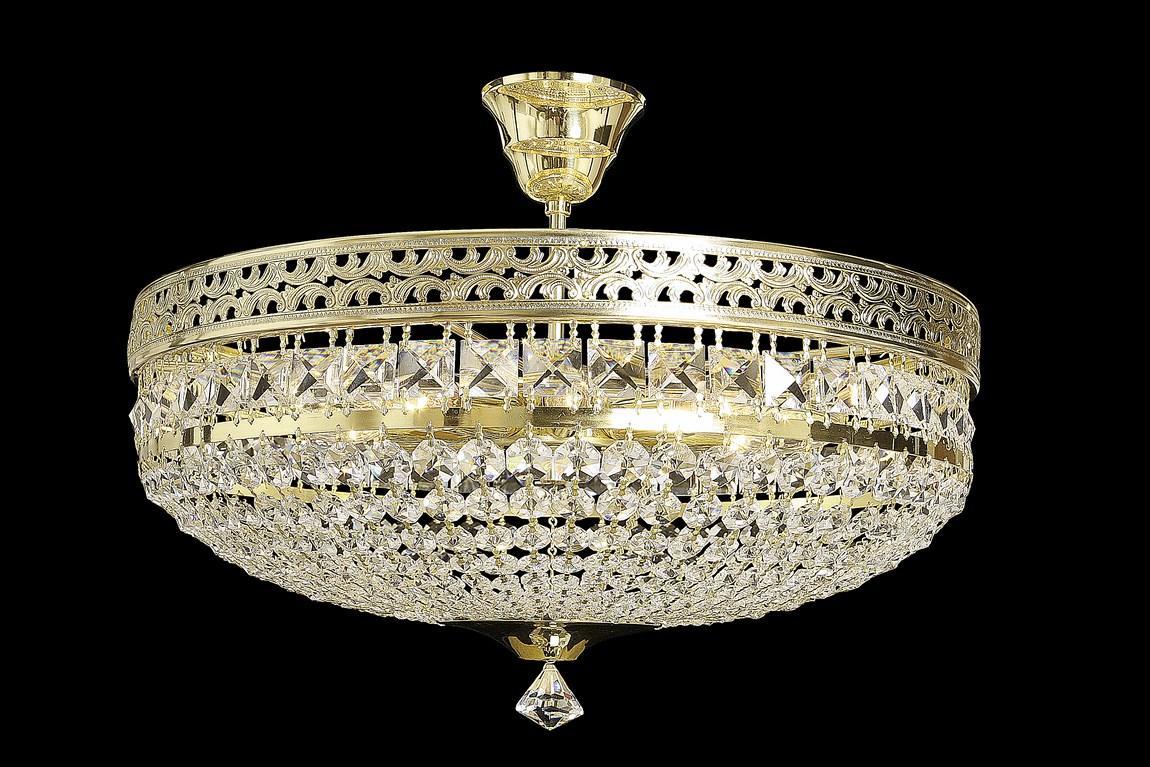 Luminaire doré de face sur fond noir, montrant la corbeille et le cabochon
