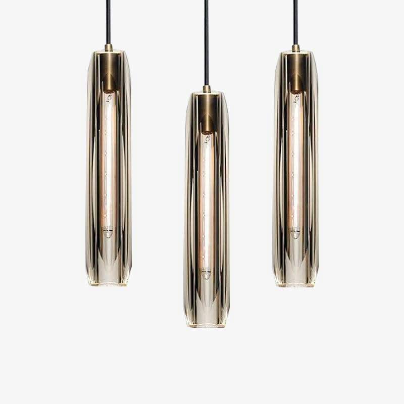 Trois luminaires suspendus à des hauteurs différentes sur fond gris neutre.