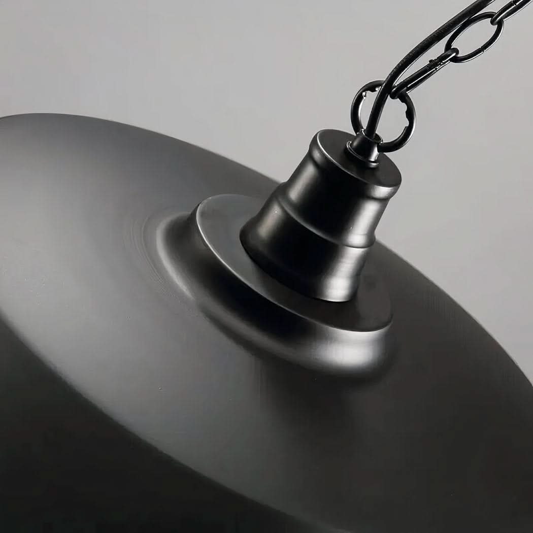 Gros plan sur la fixation et la chaîne métallique noire au sommet du luminaire.