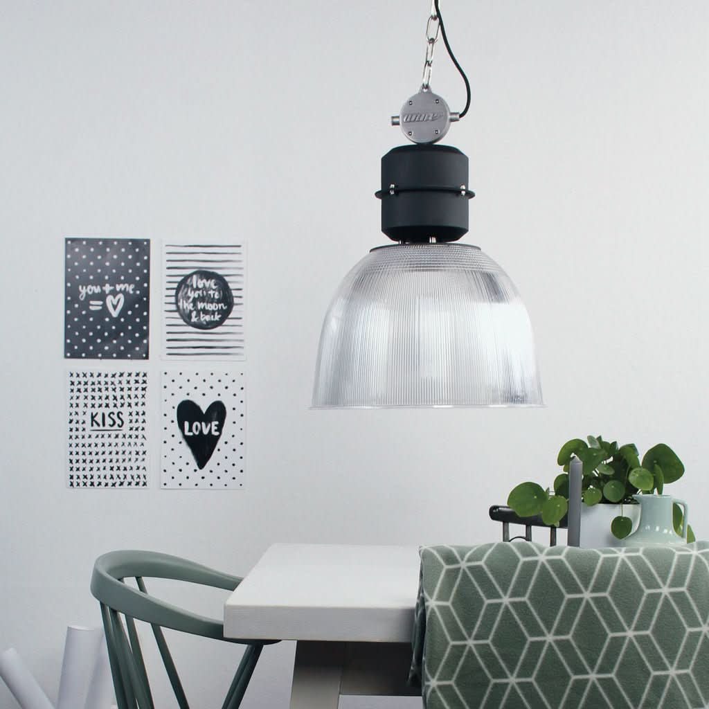 Suspension noire et verre transparent allumée au-dessus d'une table dans un intérieur