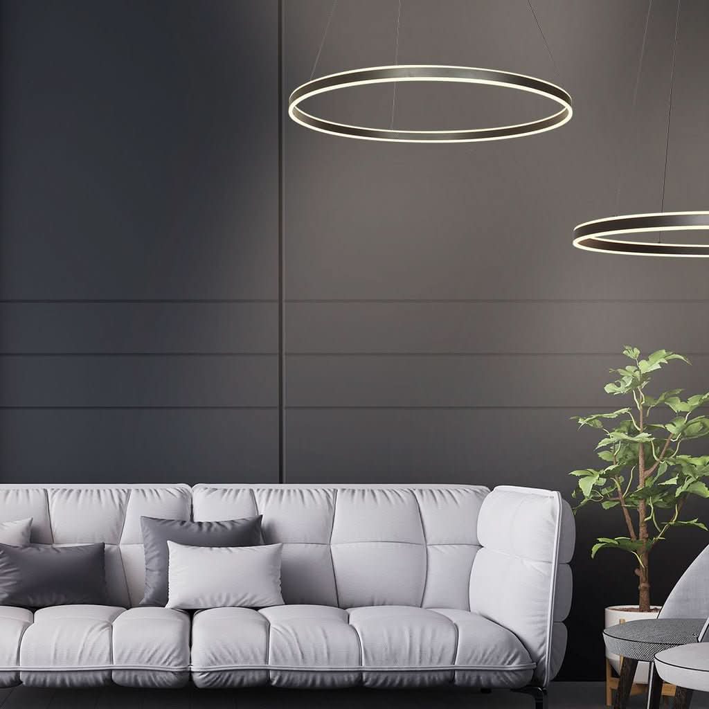 Suspension circulaire noire allumée au-dessus d'un canapé gris dans un salon.