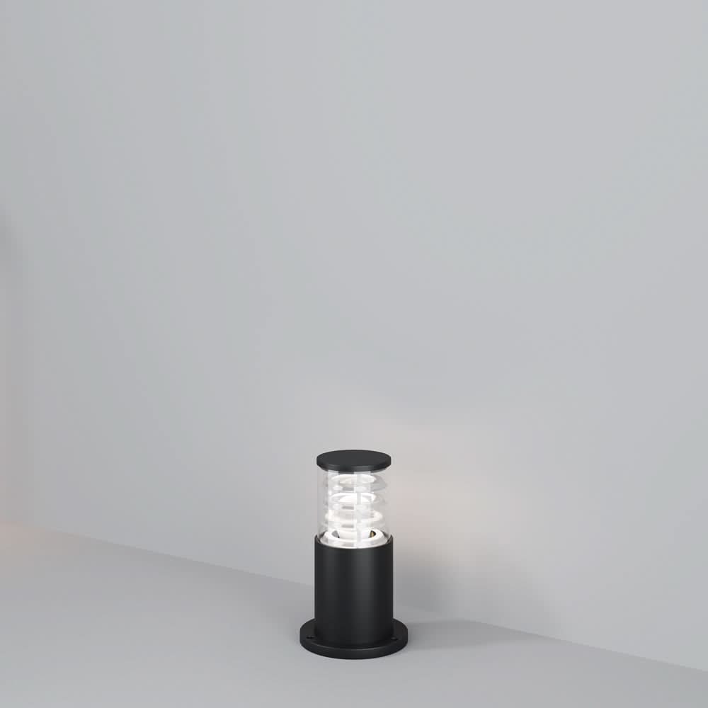Borne lumineuse noire cylindrique posée au sol, vue de face sur fond gris clair.