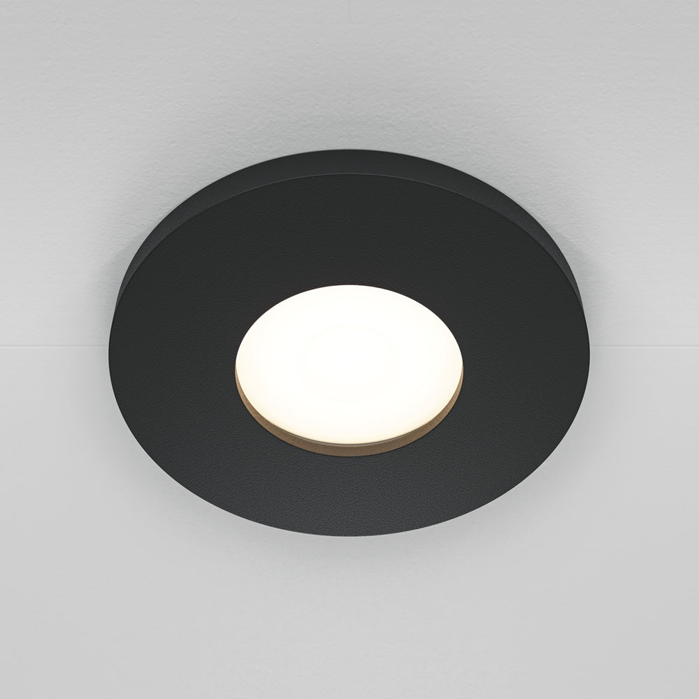 Luminaire rond noir fixé au plafond, diffuseur central blanc allumé