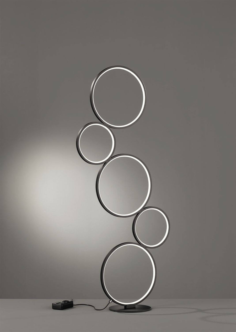 Vue de face du lampadaire à cinq anneaux noirs allumés sur fond gris.