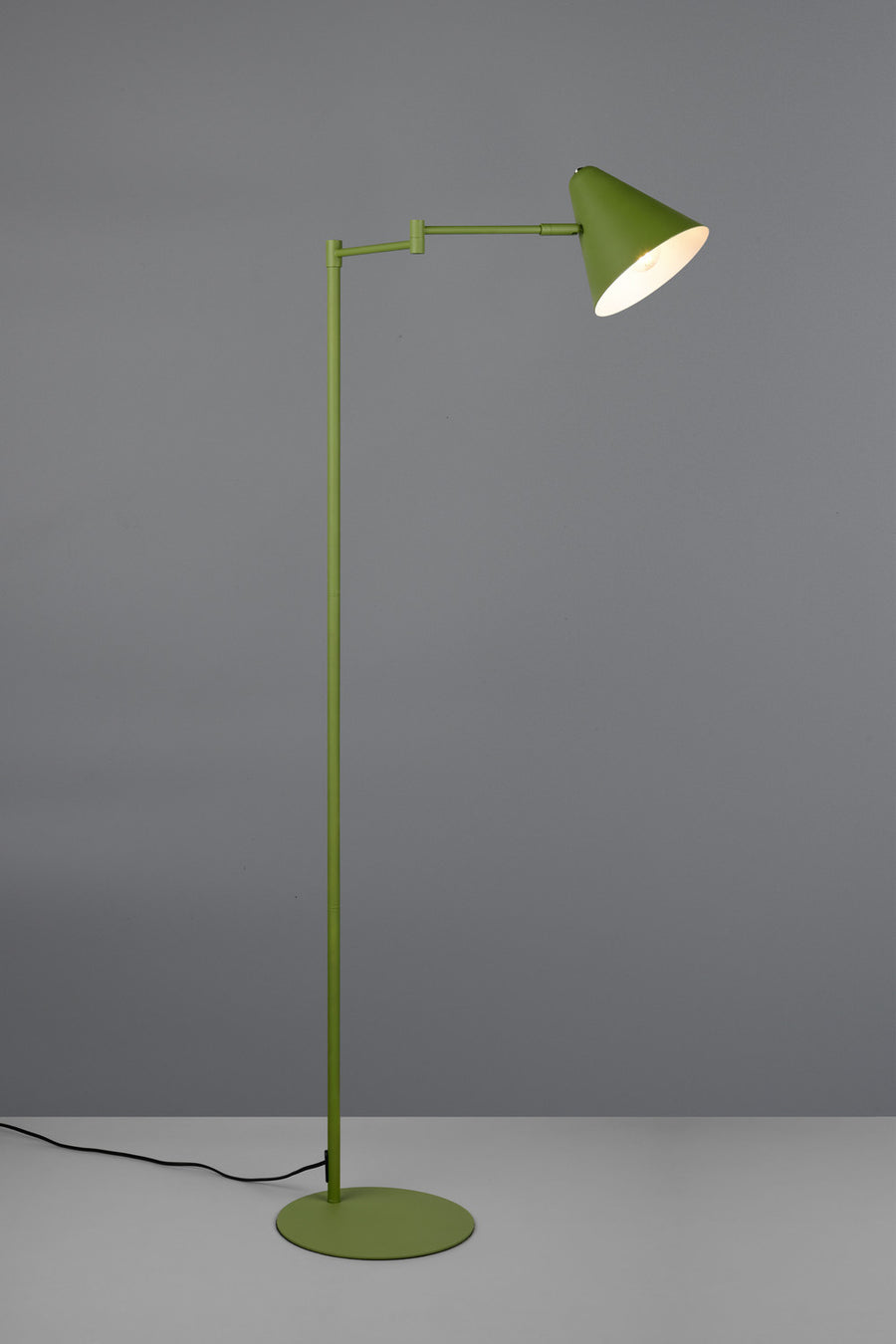 Lampadaire vert allumé sur fond gris, abat-jour conique diffusant une lumière chaude.