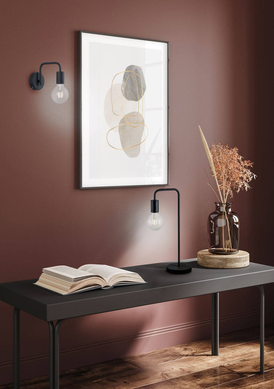 Mise en scène sur console, lampe noire allumée près d'un vase et d'un livre