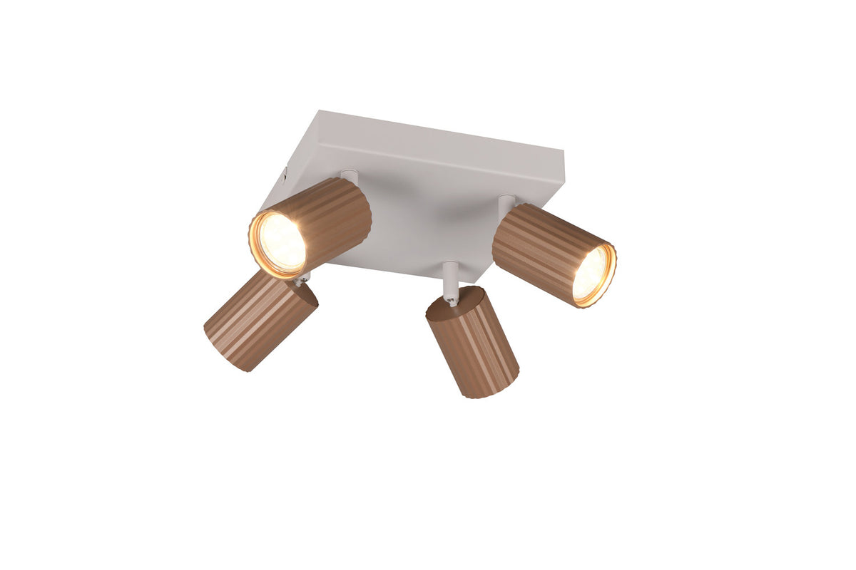 Vue de trois quarts du spot quatre lumières allumé, orientable, finition cuivrée nervurée