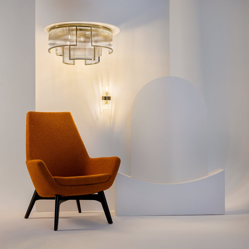 Mise en ambiance avec fauteuil rouille et applique murale assortie, décor minimaliste blanc.