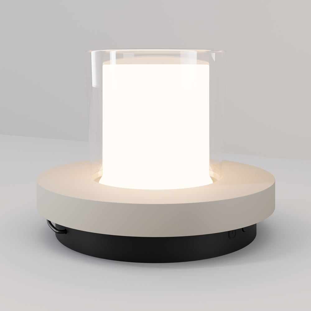 Luminaire nomade vu de face, base ronde noire surmontée d'un anneau beige et d'un diffuseur cylindrique