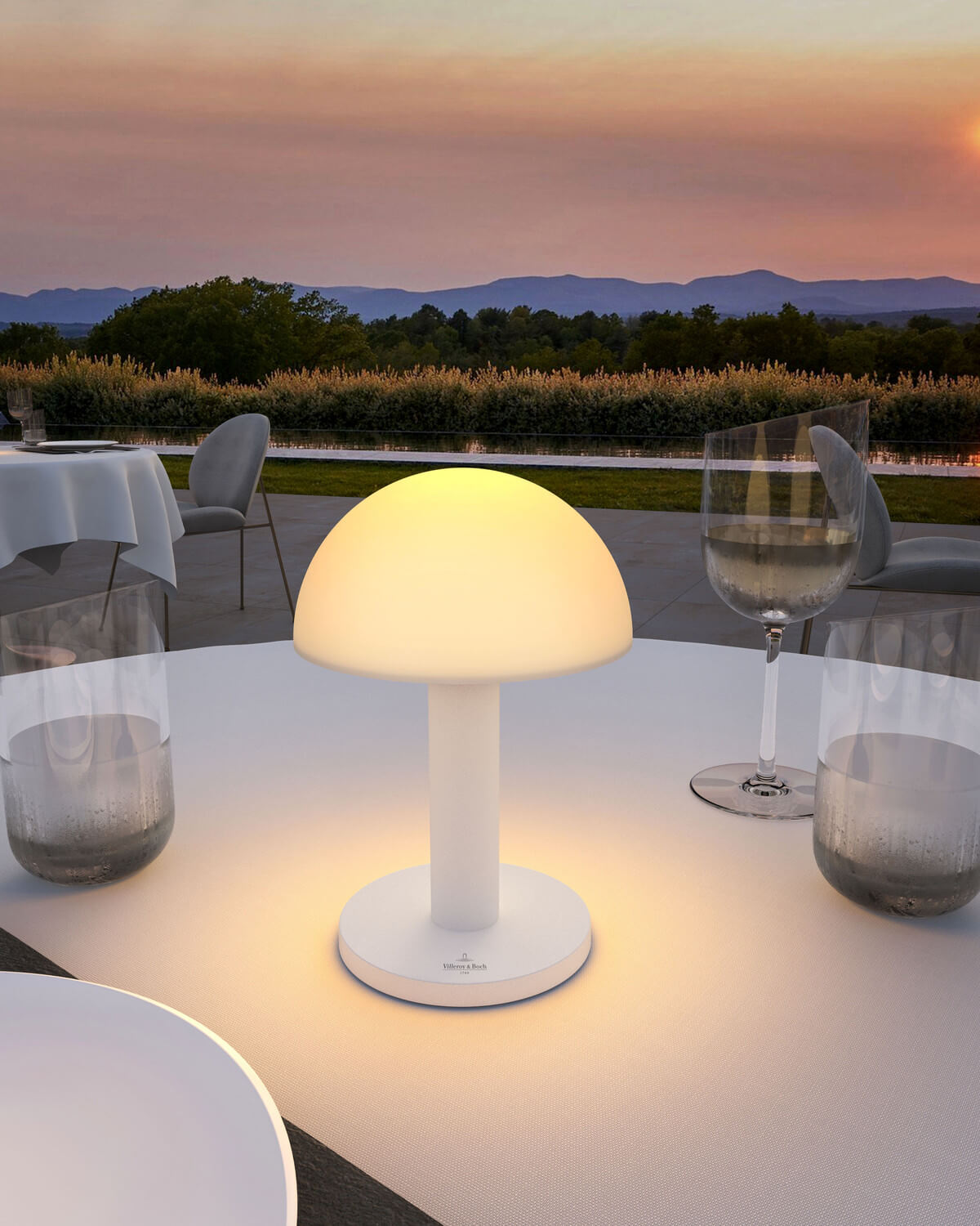 Mise en ambiance sur table extérieure dressée, allumée face au coucher de soleil